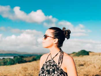 Young woman wearing sunglasses on field against sky