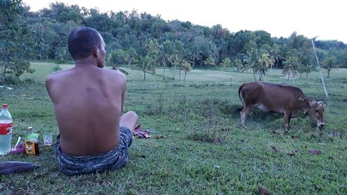 Rear view of shirtless man standing on field