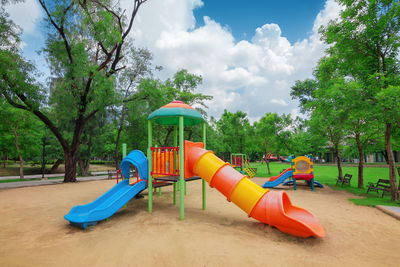 Lounge chairs by swimming pool at playground against sky