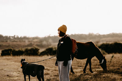 Side view of man riding horse on field against clear sky