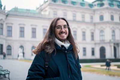 Smiling guy with long hair traveling in europe during winter time - vienna, austria