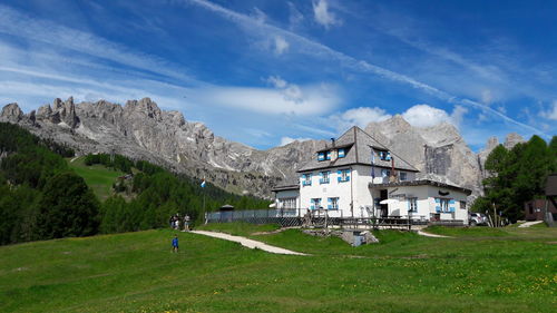 House on field by mountain against sky