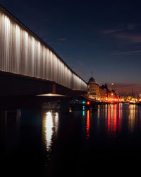 Illuminated bridge over river against sky at night