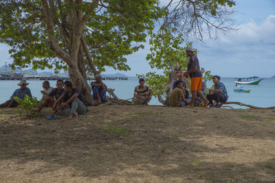 People relaxing on beach against sky