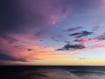 Scenic view of sea against dramatic sky during sunset