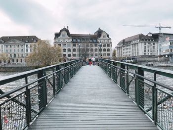 Footbridge over canal amidst buildings in city against sky