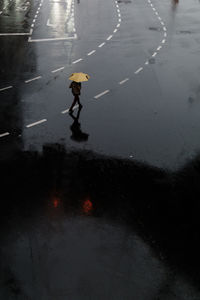 High angle view of man with umbrella walking on wet street