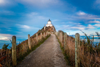 Lighthouse by sea against sky