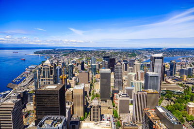 High angle view of buildings by sea against blue sky