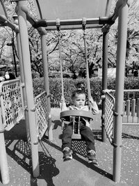 Boy sitting on swing in park