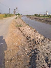 Dirt road in city against clear sky