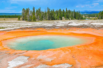 Mountain lake with geysers, red bottom, salt deposits, yellow stone nature park.