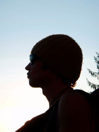 Close-up portrait of teenage girl looking away against sky