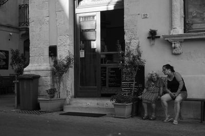 Young woman sitting on door of building