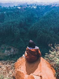 Rear view of people sitting on rock