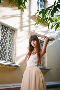 Portrait of young woman standing against building