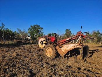 Tractor on field against clear blue sky