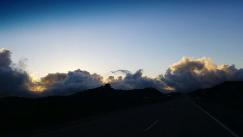 Road by mountains against sky