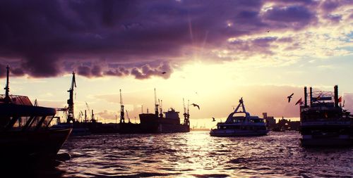 Boats at harbor against cloudy sky