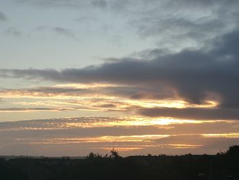 Silhouette landscape against dramatic sky during sunset