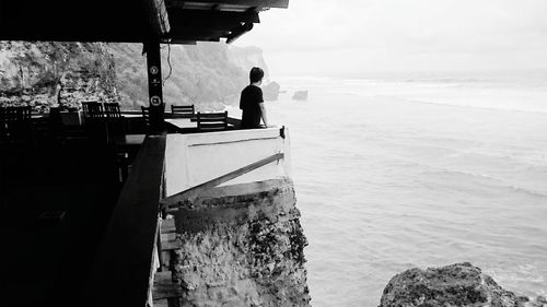 Side view of man standing at restaurant by sea