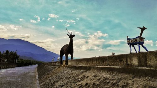 Deer standing in front of mountain against sky