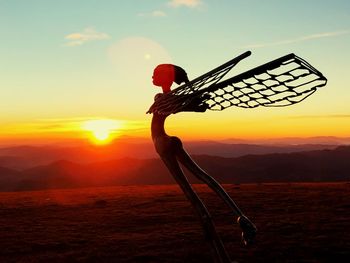 Silhouette person with umbrella against sky during sunset