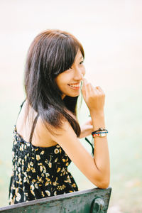 Side view of young woman drinking water while standing against white background