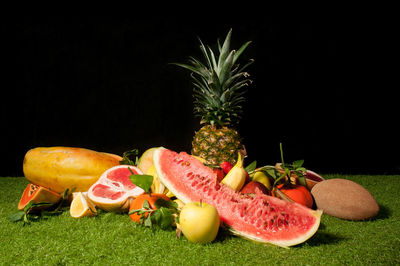 Various fruits on rug against black background