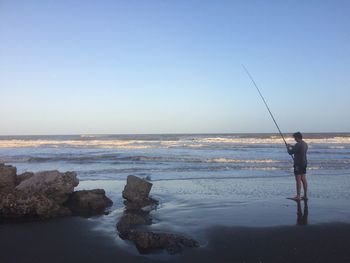Man fishing in sea against sky