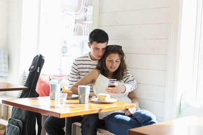 Loving couple using mobile phone at restaurant