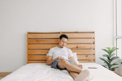 Young woman sitting on bed at home