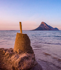 Scenic view of rocks on beach against sky during sunset