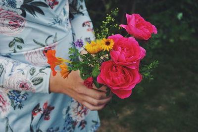 Midsection of woman holding rose bouquet