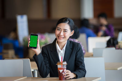 Portrait of young woman using phone on table