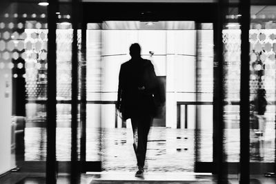 Rear view of silhouette man walking in building