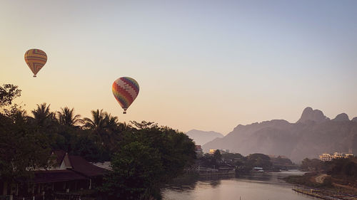 Hot air balloon flying over mountains against sky during sunset