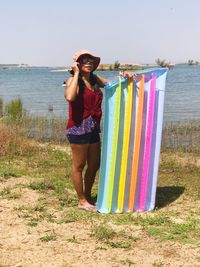 Full length of smiling standing on beach against sky