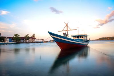Boat moored in sea against sky during sunset