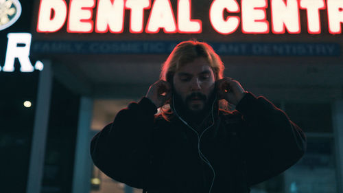 Man listening to music against light up sign