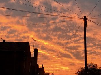 Low angle view of silhouette electricity pylon against sky during sunset