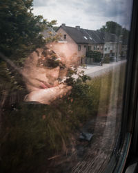 Portrait of woman seen through glass window of house