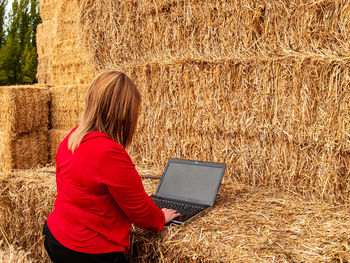 High angle view of young woman using laptop on hay bales