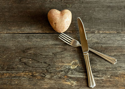 Red potatoes in the shape of a heart on a wooden background with a fork and knife. 