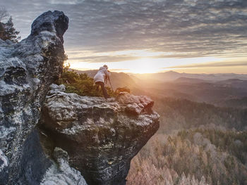 Woman photographer works. professional artist takes photos with mirror camera and tripod on peak