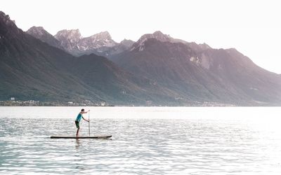 Man standing on mountain by lake against clear sky