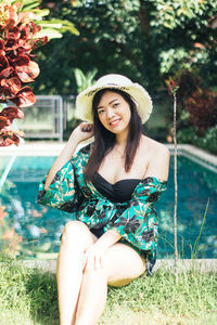 Portrait of smiling young woman sitting against plants