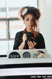 Portrait of beautiful young woman holding camera