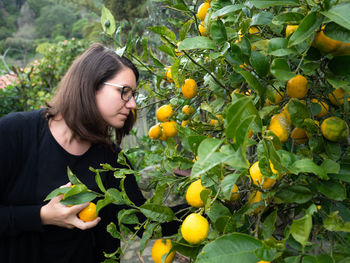 Young woman with fruits growing on plant