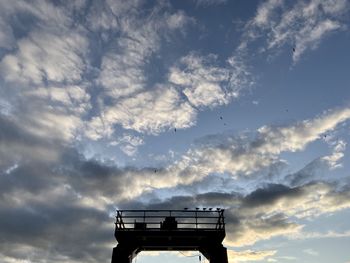 Low angle view of silhouette crane against sky at sunset